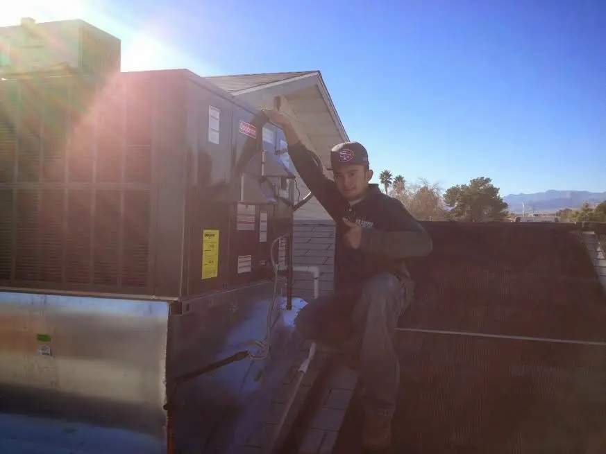 HVAC technician performing AC Tune-Up on a rooftop unit in Hales Corners